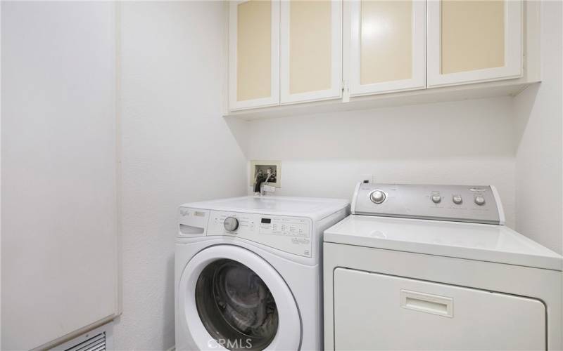 Separate interior laundry room with ample cabinet storage