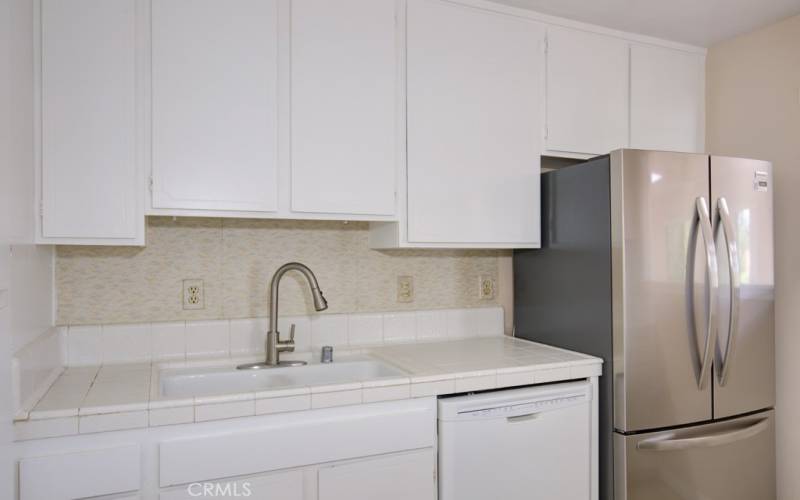 Kitchen sink, fridge and cabinetry.