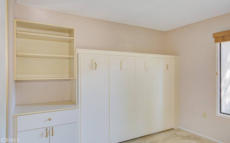 Guest bedroom features a murphy bed and ample cabinet storage.