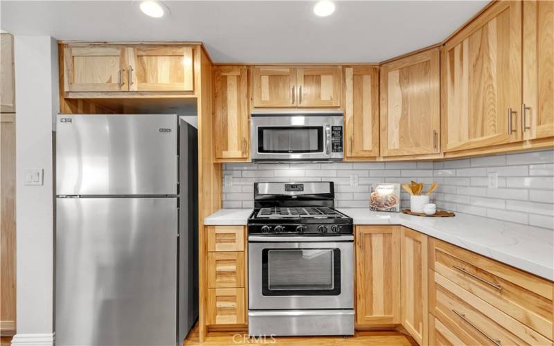 The kitchen boasts custom cabinetry, extended quartz countertp, designer backsplash, and recessed LED lights.