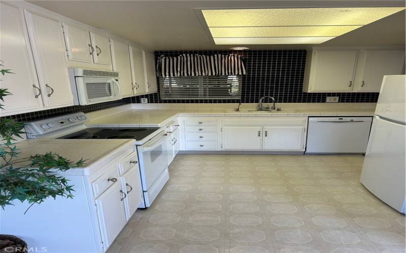 Kitchen with microwave, electric stove top, dishwasher, laminate type flooring . Includes the refrigerator.