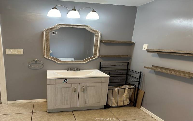 Master Bathroom with its vanity cabinet, mirror and wall shelving.