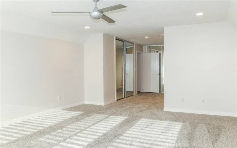 Light and bright bedroom with ceiling fan and recessed lighting.