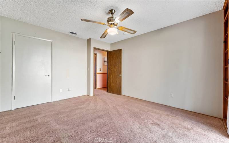 First bedroom on the right side of the hallway with sliders and built in shelves.