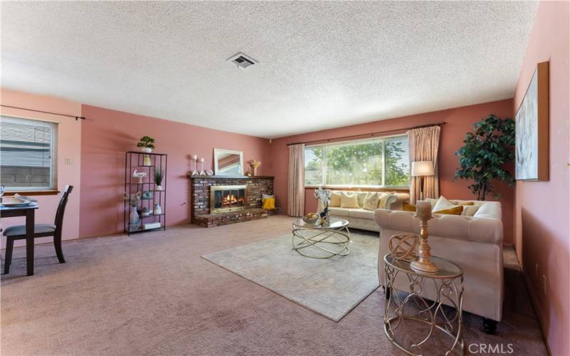 Large picture double paned window overlooking the neighborhood from living room that is large in size to accommodate the popular sectionals if you like. Living opens to dining area to the left. Fireplace has photoshopped fire.