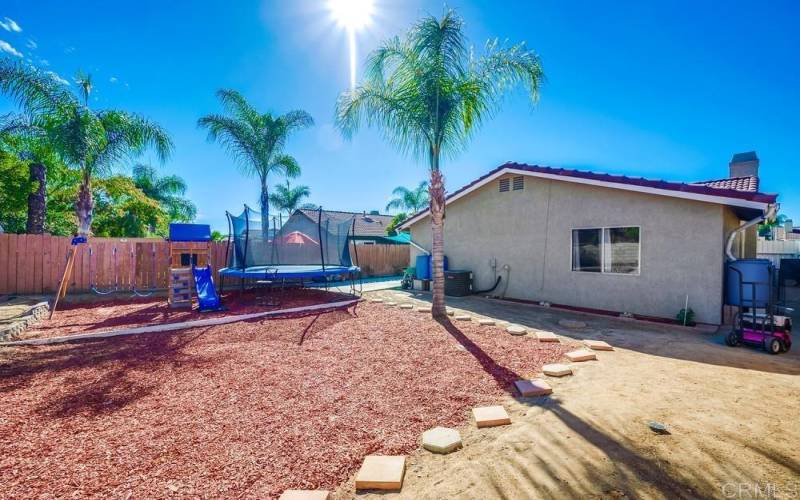 Beautiful backyard with dry landscaping highlighting the kids play area and the opposite side yard