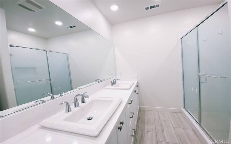 Primary bathroom has double sinks and walk-in shower.