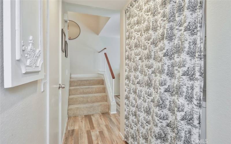 Hallway between kitchen and stairs has powder room on left and laundry on right