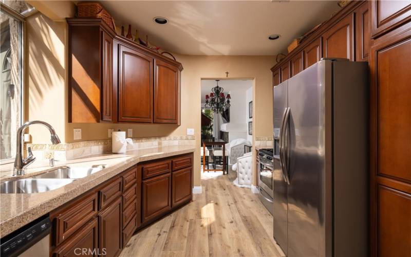 Kitchen showing Cherrywood stained cabinetry and granite top counters with tumble stone splash along with a stainless steel dual bin sink, dishwasher and garbage disposal.