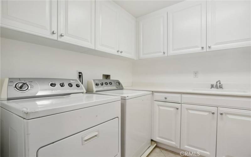 Separate laundry room with cabinets and sink