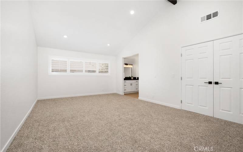 Primary bedroom with great natural lighting, vaulted ceiling, and primary bathroom