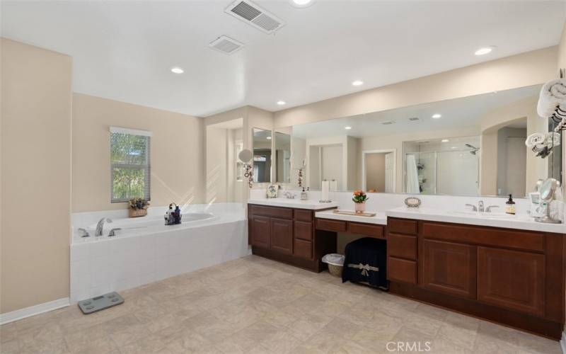 Spacious primary bathroom with dual vanity sink, recessed lighting, soaking tub and separate walk in shower.