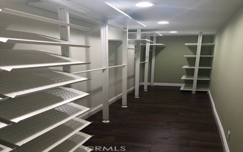 Large walk-in closet with abundant hanging space, storage shelves, and oversized shoe organizers.