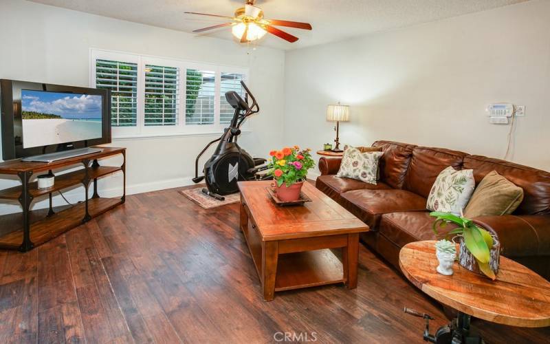 The open and bright family room adjoins the kitchen and is enhanced with a sparkling picture window, newer plantation shutters, lighted ceiling fan, newer high-end wood laminate floors, and a sliding glass door that leads to the large covered back patio.