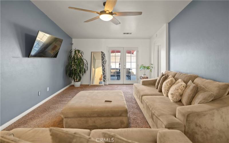 Living room w/high vaulted ceiling, ceiling fan, and new french doors that lead you out onto the uncovered patio,