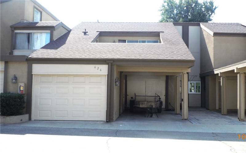 View of Townhouse, showing garage & carport.  Open balcony above is off primary bedroom.