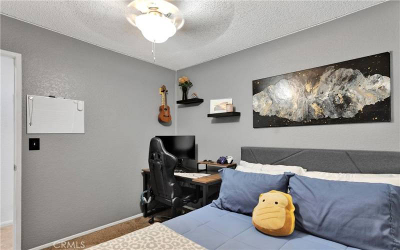 Bedroom 2 with neutral paint and lighted ceiling fan.