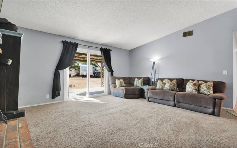 Large living room with raised hearth brick fireplace, and slider to rear covered patio.