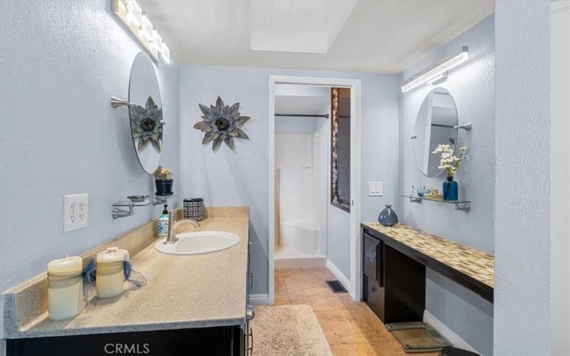 Primary bathroom with skylight overhead for lots of natural light.  Travertine flooring and lots of storage.