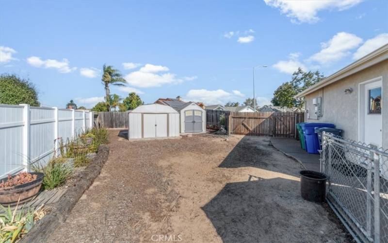 Side yard  showing RV gate and parking. Two storage sheds for all your stuff.