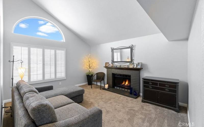 Front living room with vaulted ceilings and a gas fireplace with blue rock at the base to add to the mood.