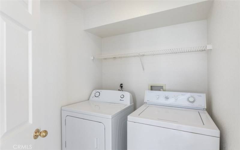 Convenient separate laundry room with shelving, offering added functionality and ease.