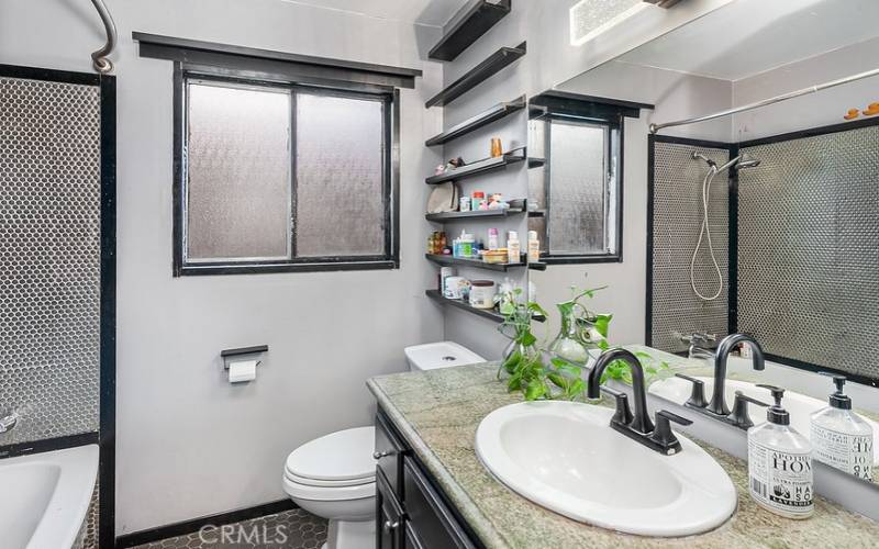 Guest bathroom with granite topped vanity, large dressing mirror, tub/shower and privacy window.