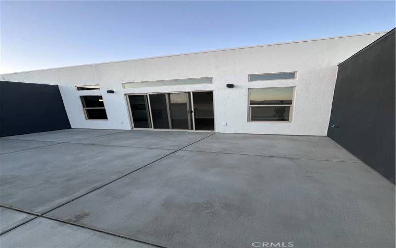 The large sliding glass doors connect the interior living spaces seamlessly with the outdoor environment, inviting ample natural light and providing direct access to the surrounding desert landscape.