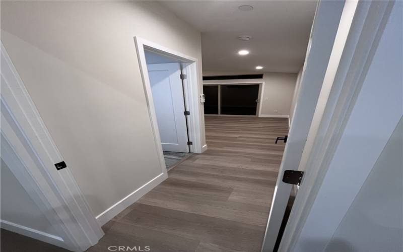 The hallway provides easy access to the private retreats within the home. Soft recessed lighting enhances the minimalist design, creating a warm and inviting ambiance.