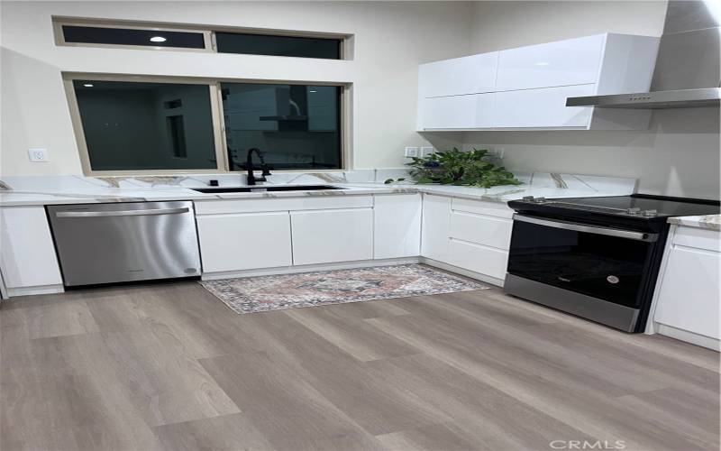 The space features sleek white cabinetry, a marble-patterned countertop, and backsplash, adding elegance and functionality.