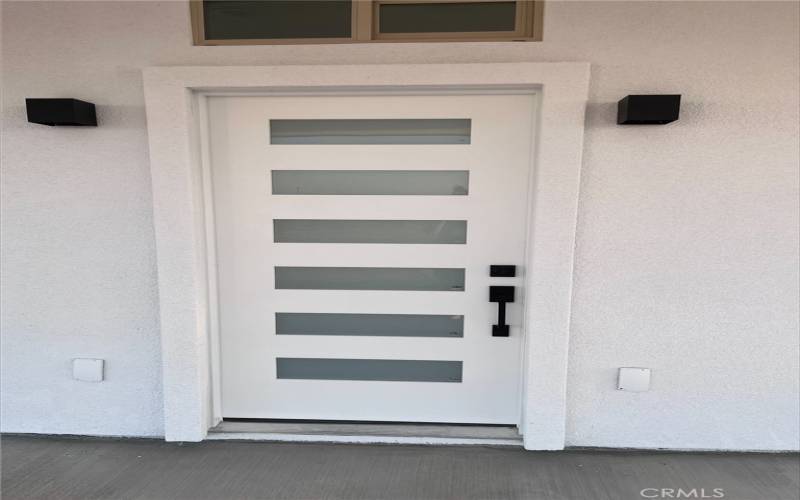 contemporary design. Featuring a sleek white finish with horizontal frosted glass panels, it brings both style and privacy to the entrance. The black hardware provides a bold contrast against the white facade, complementing the minimalist exterior