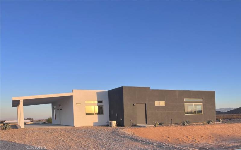 modern, minimalist architecture against the stunning desert backdrop. The clean lines and contrasting white and dark gray facade give it a contemporary aesthetic that blends harmoniously with the surrounding landscape.