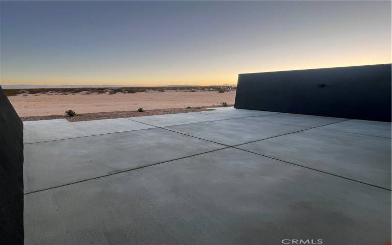 A spacious concrete patio overlooking the vast 2.16-acre lot, this space is perfect for enjoying breathtaking sunsets and the tranquility of the open desert