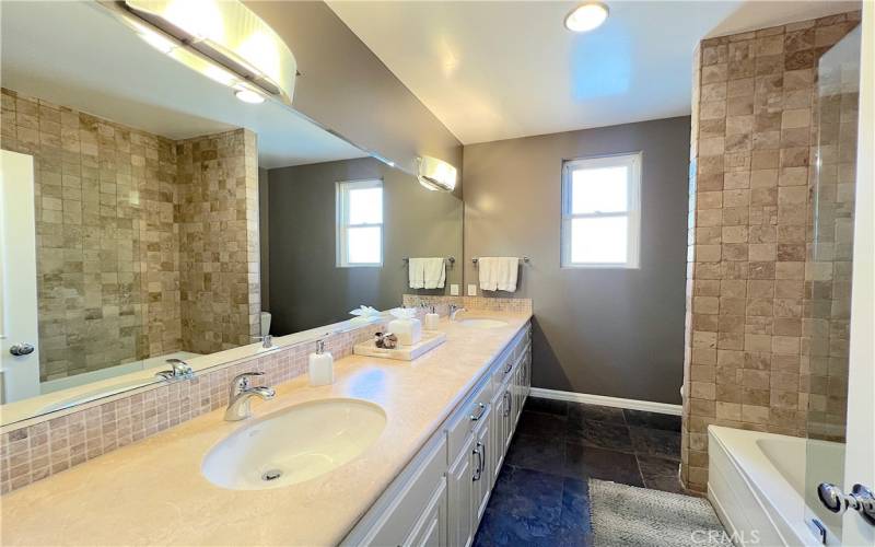 Spacious hallway bathroom between bedroom 3 and 4, with double sinks, tub and shower.