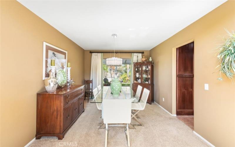 A sophisticated dining area bathed in natural light, featuring an elegant chandelier and a view of the lush outdoor space, perfect for gatherings.