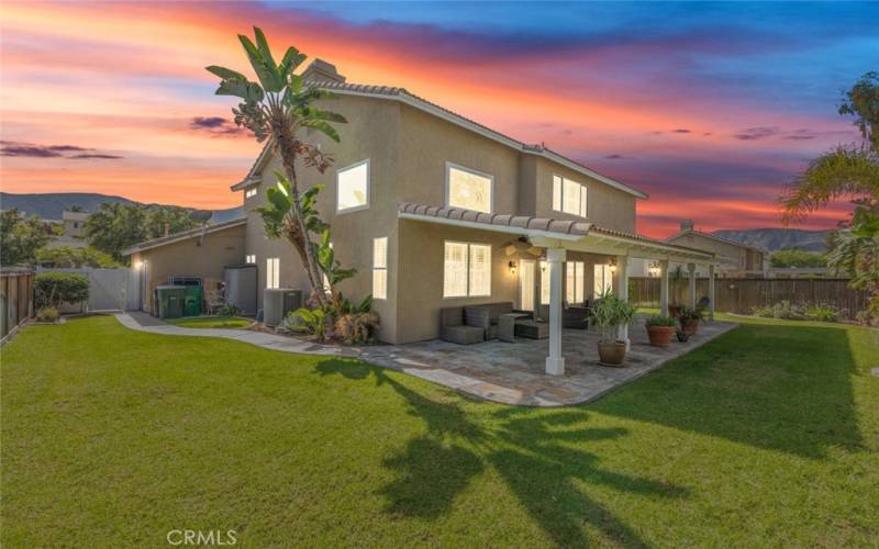 An expansive and lush backyard with a covered patio area, perfect for entertaining or relaxing.