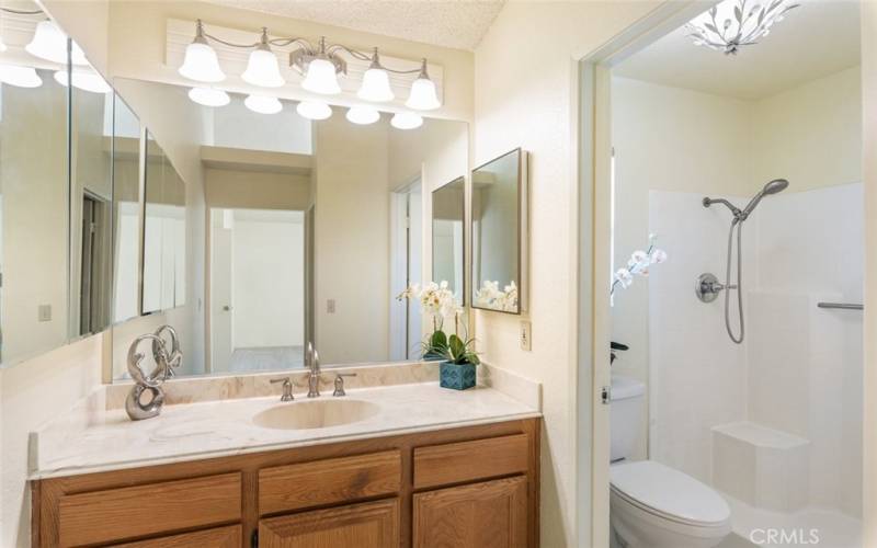 Elegant primary bathroom featuring a spacious vanity, bright lighting, and a walk-in shower.