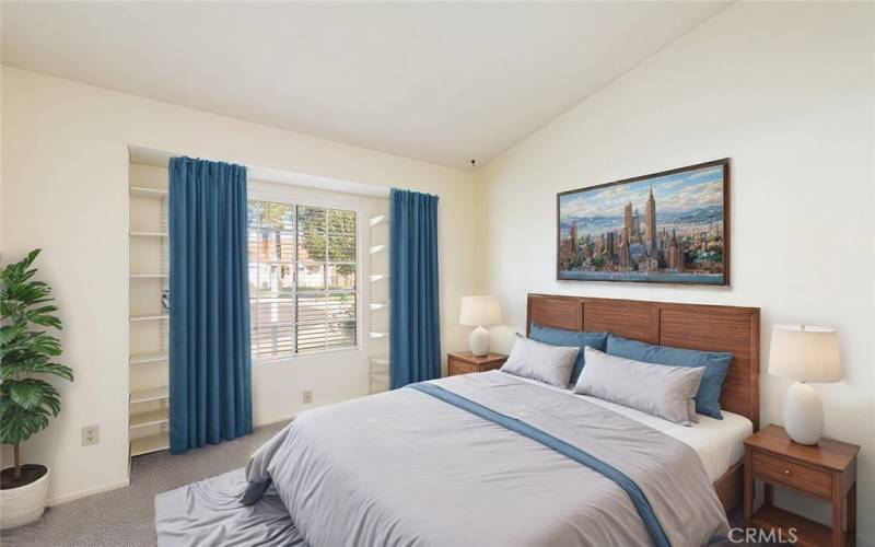 Bright bedroom with built-in shelving, large window, and cozy carpeting, offering a peaceful retreat.