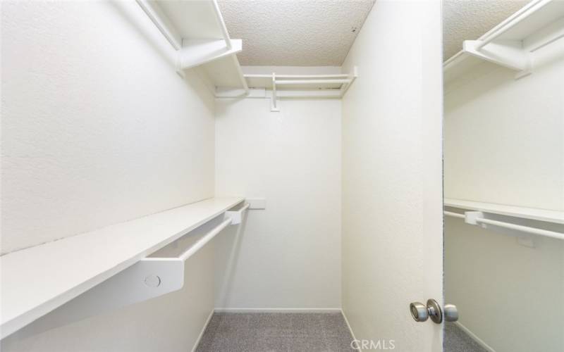 Spacious walk-in closet with ample shelving and hanging space, perfect for organized storage.