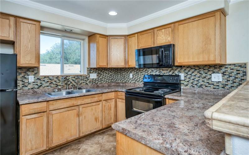 ADU kitchen with crown molding and black appliances.