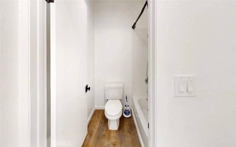 Toilet with shower to the right. separated from the bedroom by door for privacy.