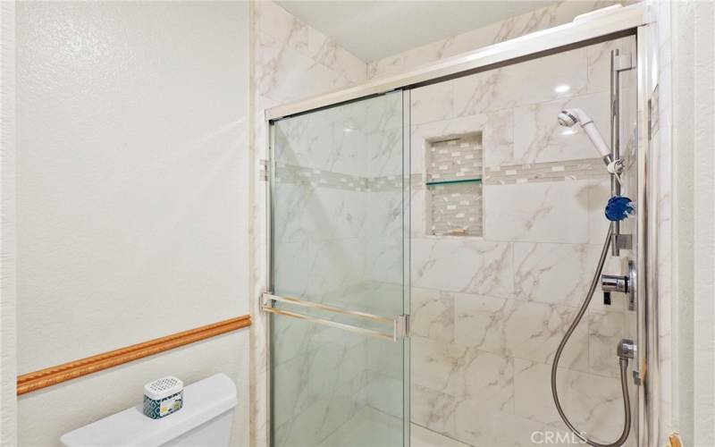 Updated shower with marble and decorative tile insert at shower shelf.