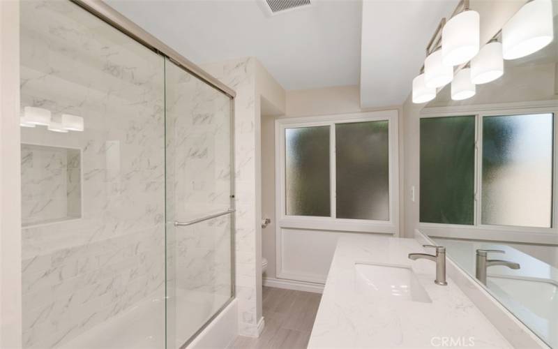 Remodeled full hallway bathroom features shower over tub