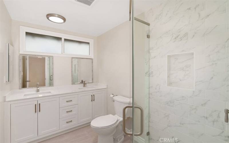 Remodeled primary bathroom with new vanity, shower, and double sinks