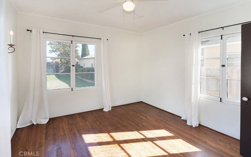 Bedroom #3 overlooks the backyard. Notice the vintage sconce, French mullion windows, original oak floors and original solid wood doors.