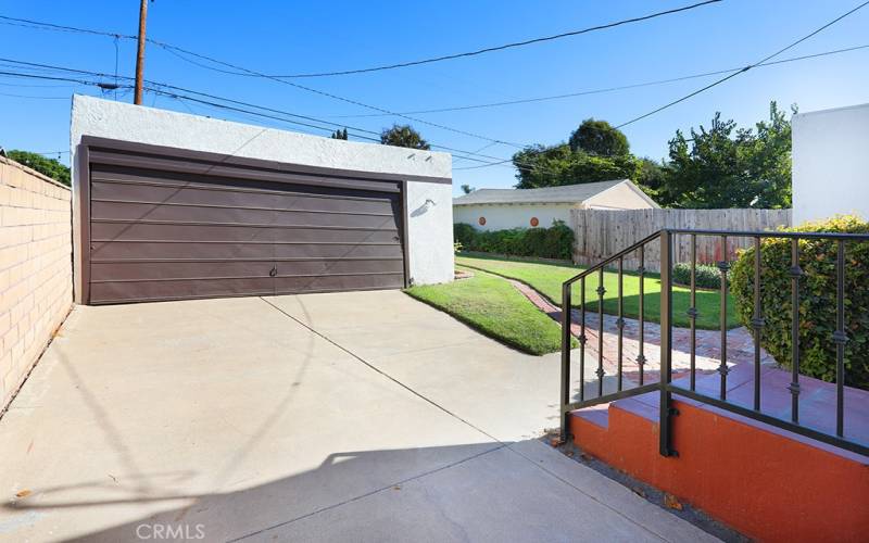 Heading outside, to the back. There’s a gated driveway and two car garage.