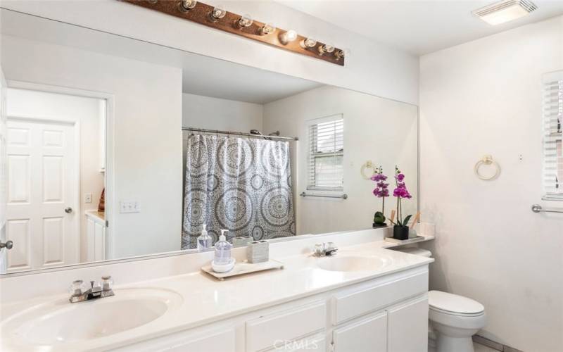 This elegant bathroom features a double sink vanity and a sleek shower, combining convenience with modern design.