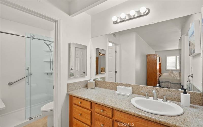 Remodeled primary bath shower with granite topped vanity