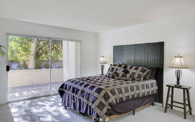 The spacious primary bedroom has a sliding glass door to the open patio area and greenbelt.