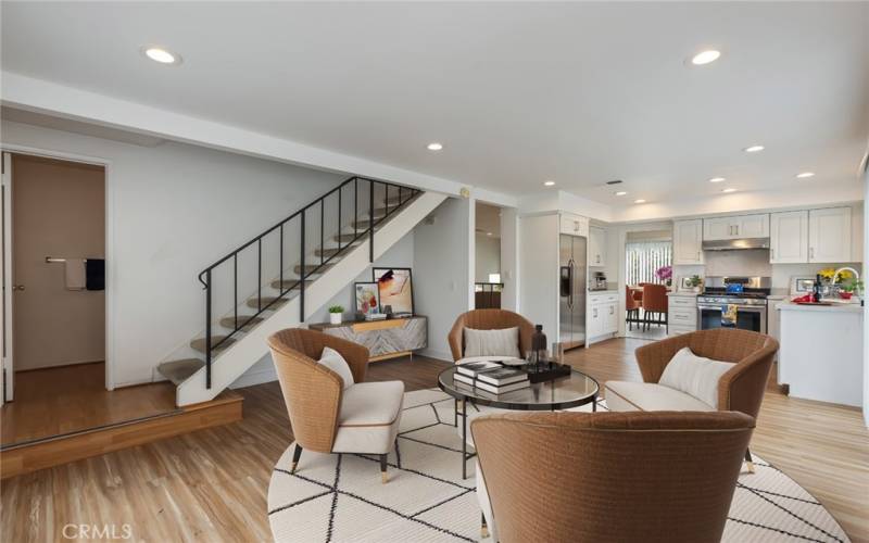 virtually staged family room off of the kitchen leading to the downstairs powderroom and bedrooms to all bedrooms upstairs